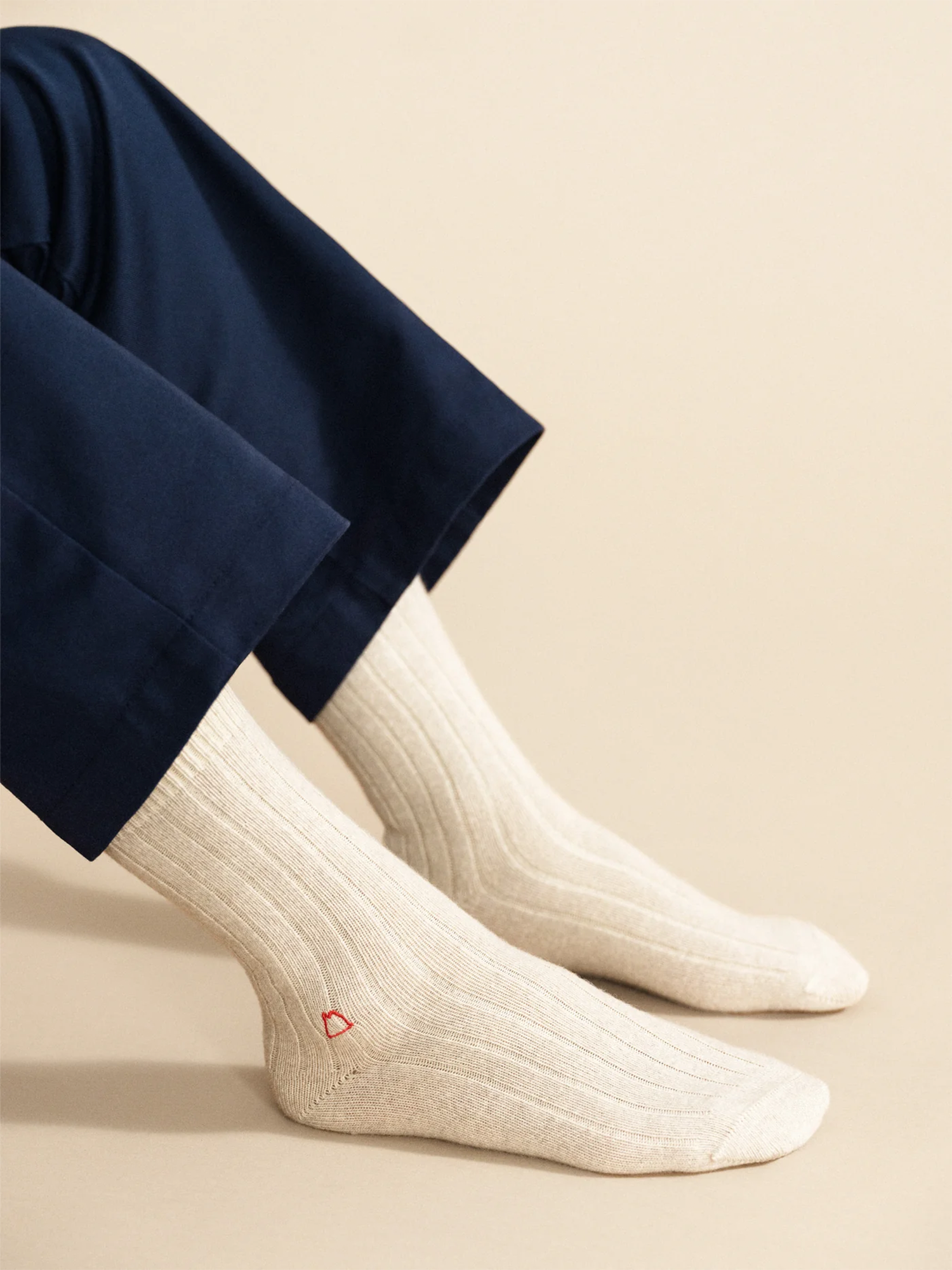 White socks with a red detail worn with navy pants on a beige background