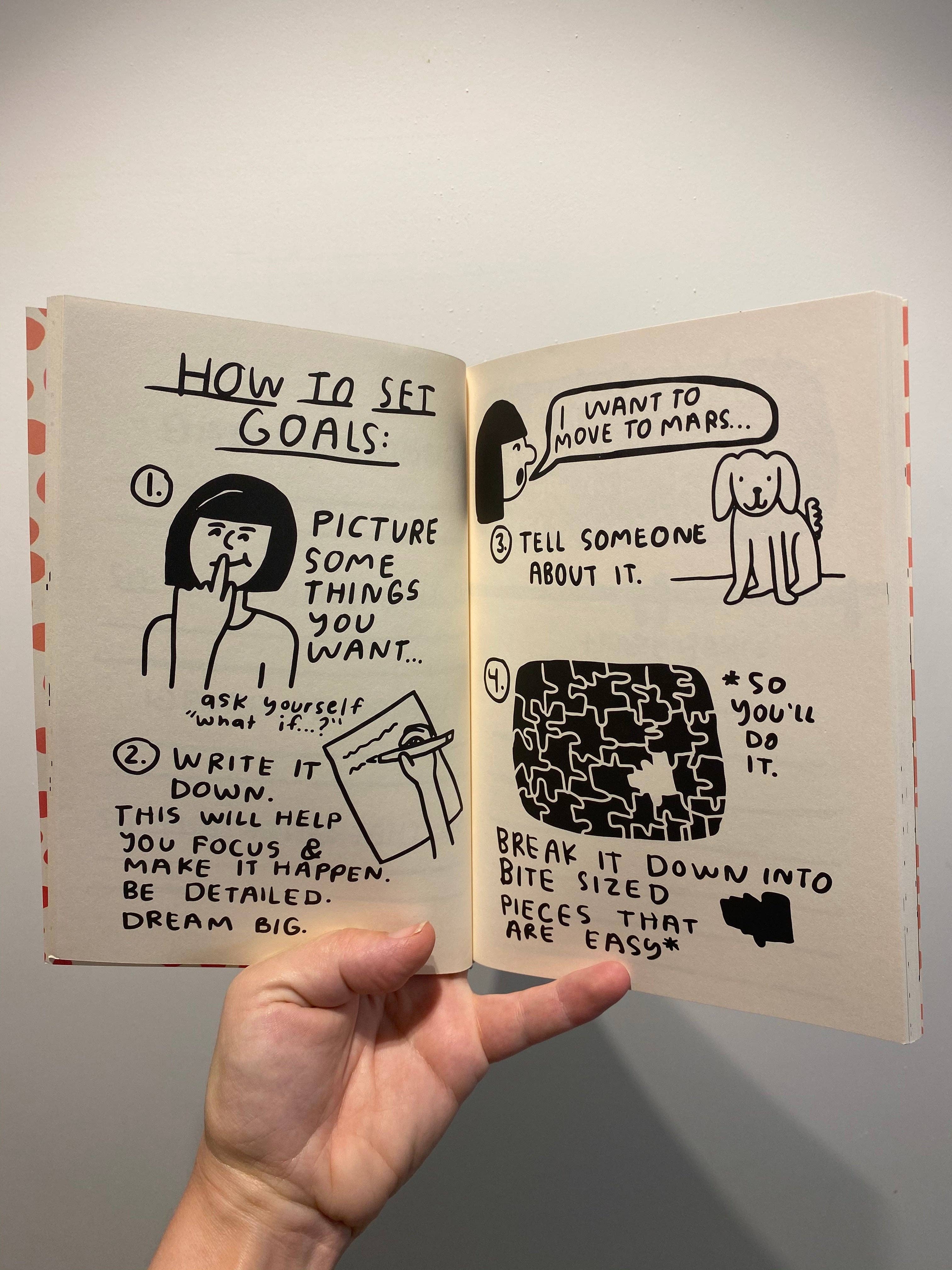 Hand holding a notebook with illustrated steps on how to set goals.