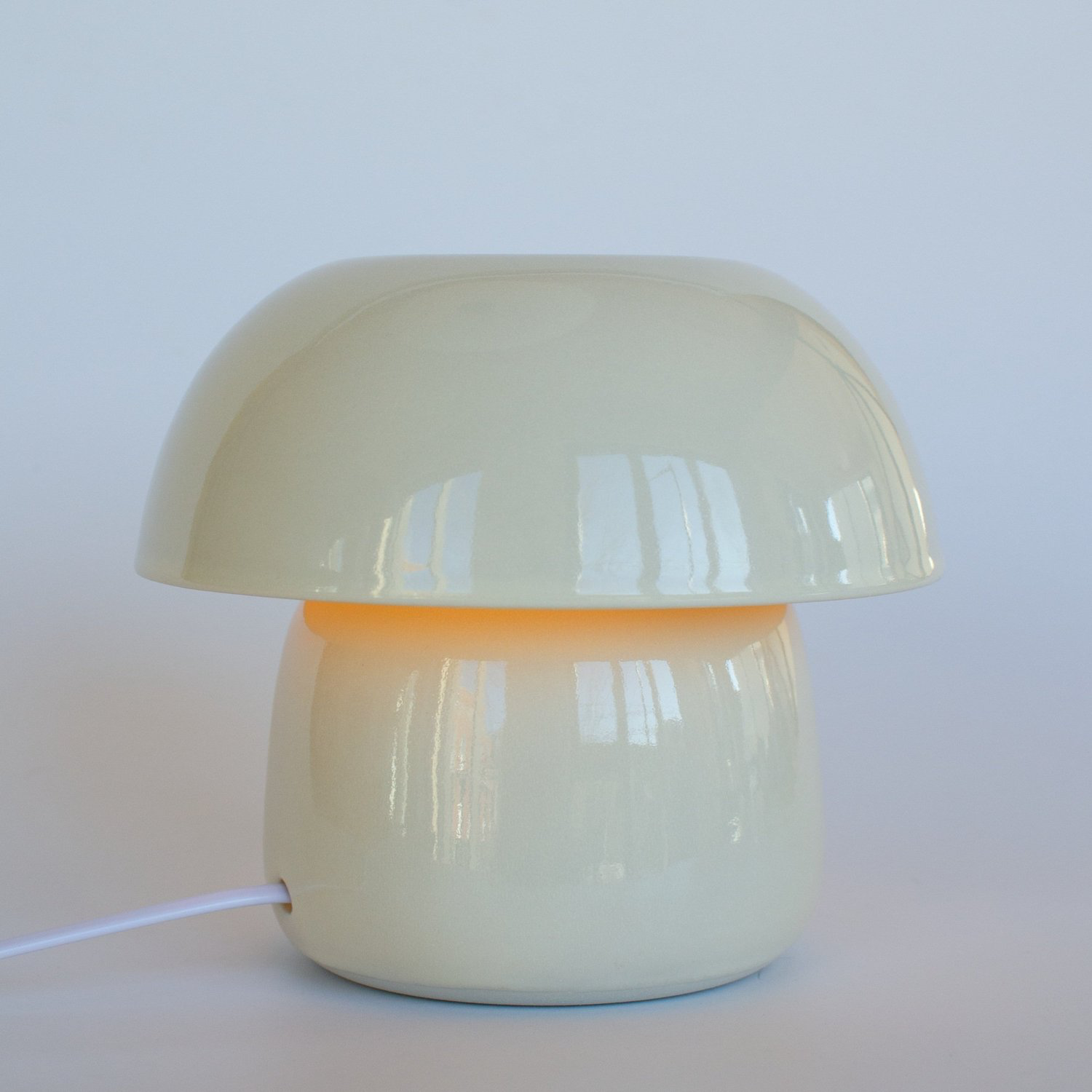 Mushroom-shaped lamp with a white base and beige top on a white background