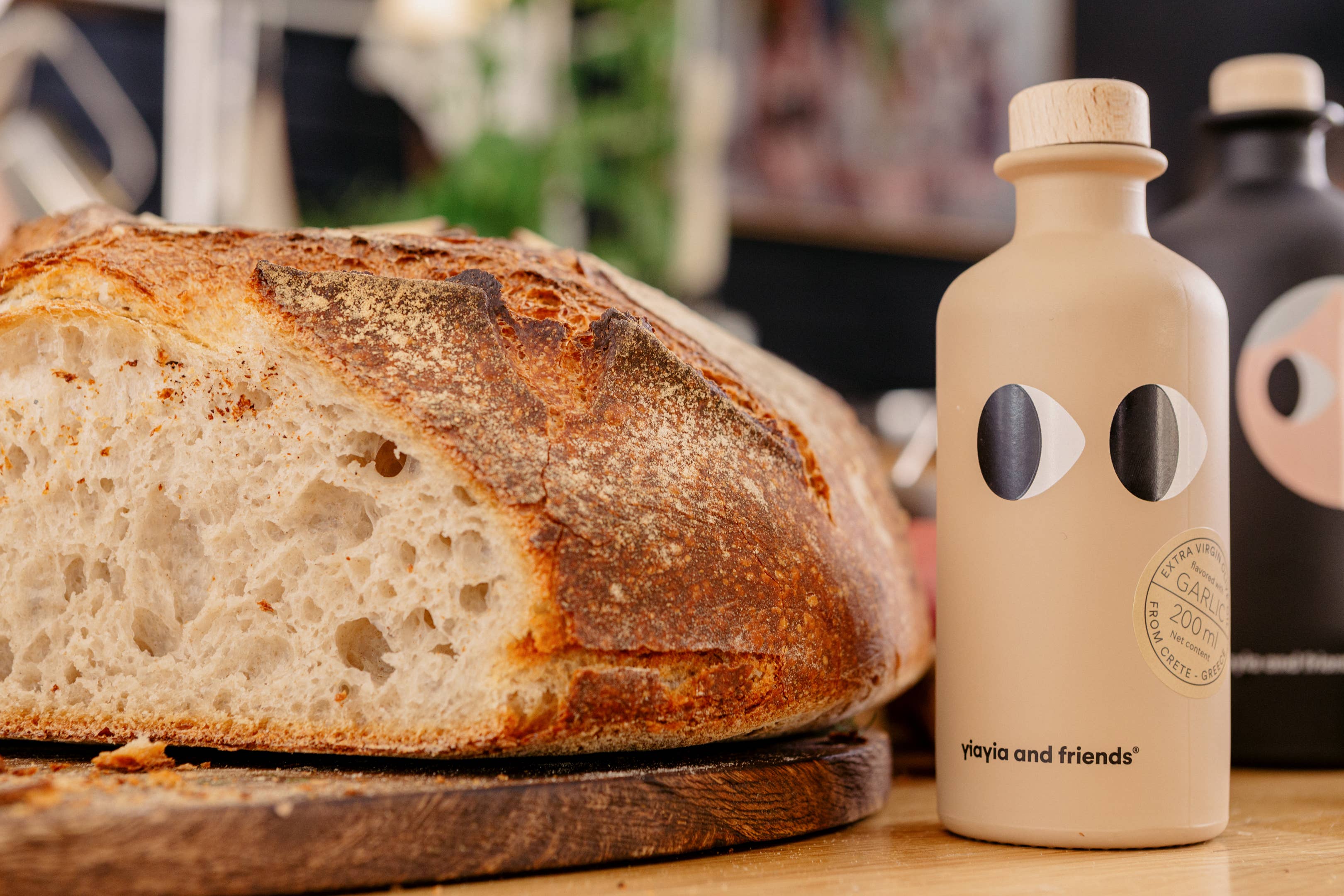 Loaf of bread on a wooden board with a beige bottle featuring black circular designs.