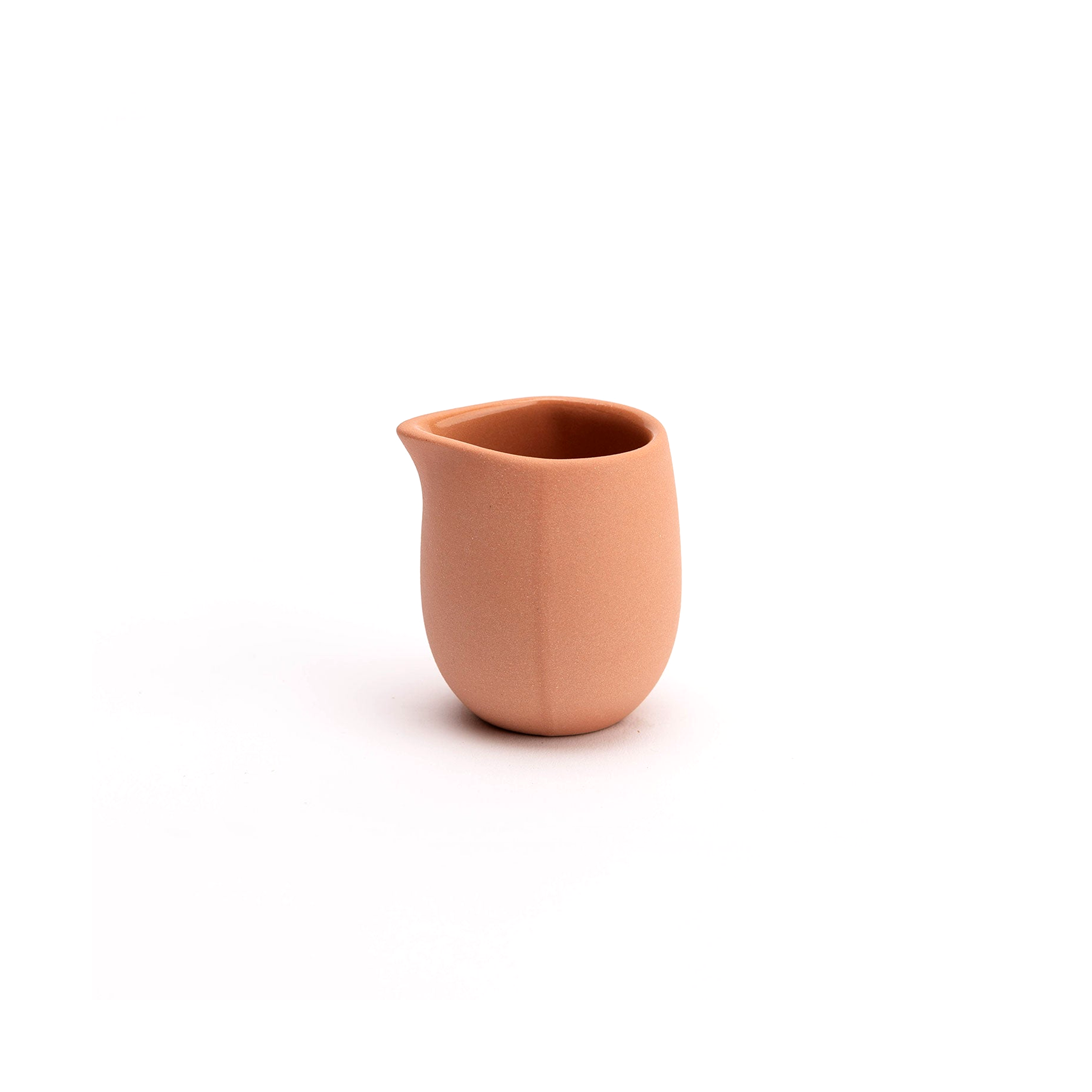 Terracotta-colored ceramic creamer on a white background