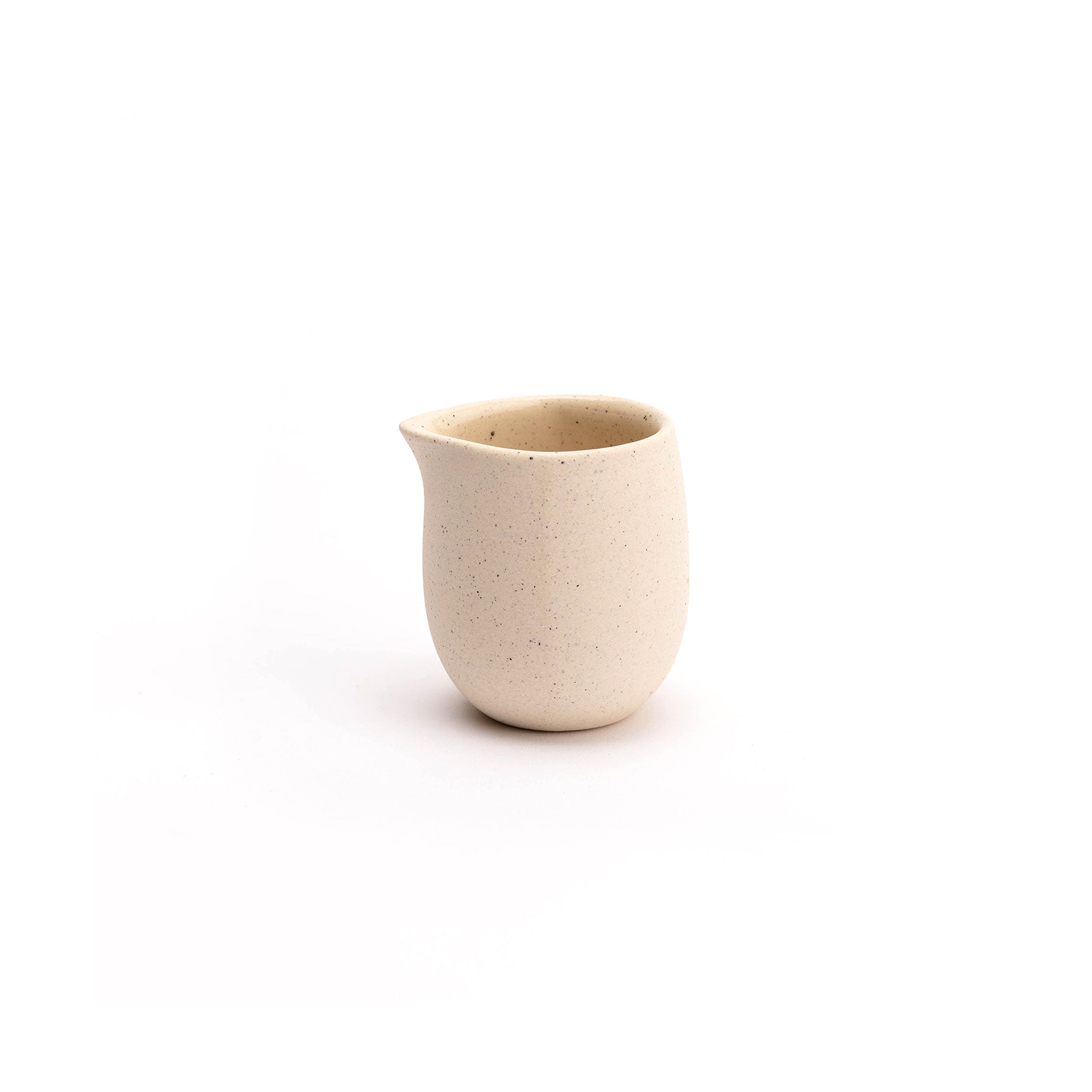 Small beige ceramic creamer on a white background